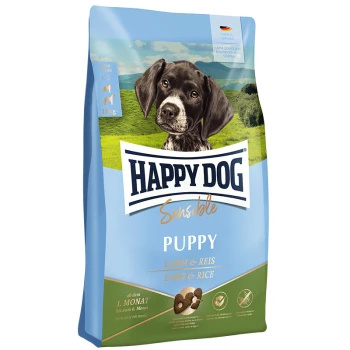 Torba z karmą Happy Dog Sensible Puppy z czarno-białym szczeniakiem na tle zielonego krajobrazu, oznaczona 'Lamm & Reis' (Jagnięcina i Ryż).