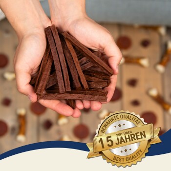 Eine Tüte "Premium Quality" Haustierleckerlis, die braune Jerky-Streifen auf einer Holzoberfläche auskippt, mit einem teilweise sichtbaren weißen Seilspielzeug.