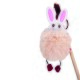 Ein verspieltes Katzenspielzeug mit einem flauschigen rosa Pom-Pom mit einem weißen Hasengesicht und Ohren, das an einem Holzstock befestigt ist.