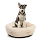 Ein sitzender Hund auf einem plüschigen, runden Haustierbett mit einem weichen beigen Äußeren und schwarzem Boden, das Komfort und Stil zeigt.