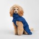 Ein flauschiger Hund in einem blauen Haustiermantel sitzt vor einem schlichten weißen Hintergrund und zeigt das Design und die Passform des Mantels.