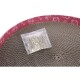 Eine durchsichtige Plastiktüte mit getrocknetem Katzenminze sitzt auf einem runden, strukturierten Kratzpad mit einem rosa Rand, das verspielte Katzenillustrationen zeigt.
