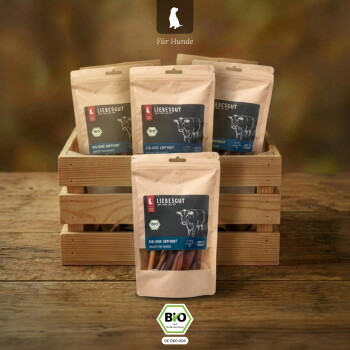 Wiederverschließbare Kraftbeutel mit Liebesgut Bio-Rind-Hundesnacks (Bio-Label) mit Kuh-Illustration in einer Holzkiste, „Für Hunde“.