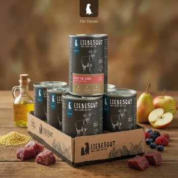 Stapel LIEBESGUT Dosenfutter in Kartontray (Hirsch für Hunde), umgeben von Birnen, Apfel, Beeren, Öl und Fleisch.