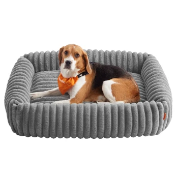 Beagle trägt ein orangefarbenes Halstuch und liegt auf einem grauen, gerippten, plüschigen rechteckigen Haustierbett.