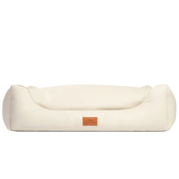 Cremefarbenes Haustierbett mit erhöhten Rändern und einem Lederetikett mit der Aufschrift 'Freudenfetter.'