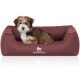 Ein kleiner, flauschiger Hund sitzt bequem in einem burgunderfarbenen Hundebett mit dem Logo "KNUFFELWUFFF", das auf der Vorderseite sichtbar ist.