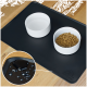 Eine schwarze Futtermatte für Haustiere mit zwei weißen Schalen, eine gefüllt mit trockenem Haustierfutter und die andere leer für Wasser, mit einer Nahaufnahme von verschütteter Flüssigkeit.