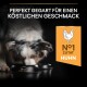 Ein Merle-Hund schnüffelt an einer schwarzen Schüssel mit dem Text: "Perfekt gegart für einen köstlichen Geschmack" und "N°1 Zutat Huhn."