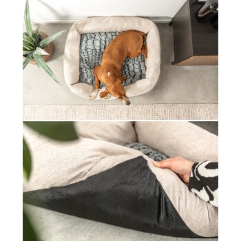 Ein kleiner brauner Hund schläft in einem gemütlichen beigen Haustierbett mit einem grauen Kissen, während eine Person die schwarze Unterseite des Bettes hält.