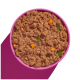 Eine rosa Schüssel gefüllt mit feuchtem Haustierfutter mit einer groben Textur, gemischt mit kleinen Stückchen Gemüse und Kräutern.