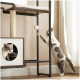 Eine verspielte grau-weiße Katze greift nach einem hängenden Spielzeug auf einem modernen Katzenbaum, während eine andere Katze aus einer runden Öffnung herauslugt.