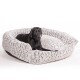 Ein schwarzer Labrador Retriever, der bequem in einem plüschigen, grauen Haustierbett mit strukturiertem Design ruht.