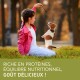 Un enfant en veste rose est assis sur l'herbe, tenant une friandise pour un chiot excité. Texte : "Riche en protéines, équilibre nutritionnel, goût délicieux !"