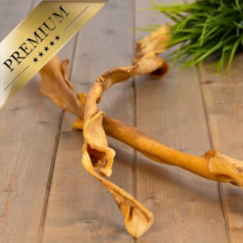 Ein verdrehter, getrockneter Hundekau-Stick liegt auf einer Holzoberfläche, mit einer grünen Pflanze im Hintergrund und einem goldenen 'PREMIUM'-Abzeichen in der Ecke.