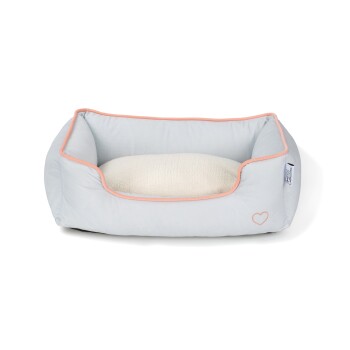 Jasnoszara legowisko dla zwierząt z miękką białą poduszką, z różowym wykończeniem i małym logo serca z boku.