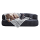 Zwei Hunde entspannen auf einer dunkelgrauen Couch mit einer hellgrauen Decke: ein großer hellbrauner Hund und ein kleiner schwarzlockiger Hund.
