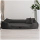 Ein plüschiges, dunkelgraues Haustierbett mit erhöhten Seiten und einem kleinen dekorativen Kissen, vor einem minimalistischen Hintergrund mit einer Pflanze und einer modernen Lampe.