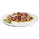 Une assiette blanche remplie de morceaux de viande tendres et hachés dans un bouillon savoureux, garnie de feuilles de basilic frais.