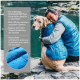 Eine Frau in einer blauen Weste umarmt einen Golden Retriever an einem Fluss, was Wärme, Isolierungstechnologie und wasserdichtes Material zeigt.
