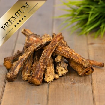 Ein Haufen hochwertiger Hundekauartikel aus natürlichen Knochen, auf einer Holzoberfläche mit einer grünen Pflanze im Hintergrund präsentiert.