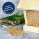Holz-Vogelfutterspender gefüllt mit Samen, mit verschütteten Samen auf dem Boden und grünem Gras im Hintergrund. Text: "Ideal als Vogelfutter-Ergänzung."