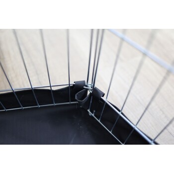 Nahaufnahme einer Ecke einer Haustierbox, die Metallstäbe und eine schwarze Stoffauskleidung zeigt, die mit Riemen gesichert ist.