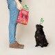Une personne en jeans bleus tient un sac de nourriture pour chiens Edgard Cooper étiqueté "Boeuf & Poulet", tandis qu'un pug noir curieux regarde avec surprise.