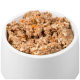 Eine weiße Haustierfutterschüssel, gefüllt mit einer feuchten, stückigen Mischung aus Fleisch und Reis, mit Stücken von orangefarbenem Gemüse.