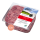Eine weiße Schüssel gefüllt mit rohem, gehacktem rotem Fleisch, auf einer Holzoberfläche platziert.