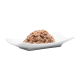 Un tas de nourriture pour animaux sur une assiette blanche, présentant un mélange texturé et humide adapté aux chats ou aux chiens.