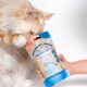 Eine flauschige cremefarbene Katze schnüffelt an einem Beutel mit der Aufschrift "VITAMIN-MILCHSHAKE ABWEHRKRÄFTE", der eine Cartoon-Katze und Nährwertangaben zeigt.