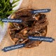 Eine Holzschale mit getrockneten Fleischstreifen mit deutschen Etiketten: "reich an Protein", "energiefördernd" und "sanft getrocknet." Grüne Pflanze im Hintergrund.