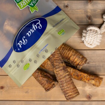 Eine Tüte mit Haustierleckereien, die mit "Premiumqualität" beschriftet ist, mit sichtbaren Hundekau-Sticks, die herausfallen, auf einer Holzoberfläche platziert.