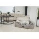 Ein entspannter weißer Hund liegt auf einem plüschigen grauen Haustierbett in einem modernen Wohnzimmer, mit einem beigen Sofa und einem schwarzen Couchtisch in der Nähe.