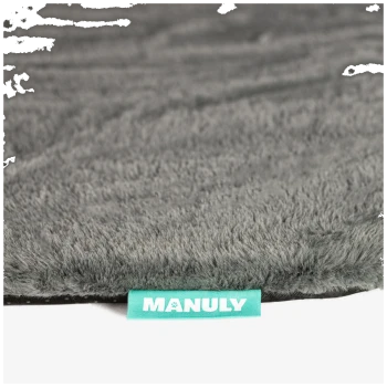 Rand einer grauen, plüschigen Haustiermatte mit türkisfarbener Stofflasche mit Aufschrift 'MANULY'.