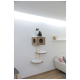Eine getigerte Katze sitzt auf einem modernen Holz-Katzenbaum mit einem würfelförmigen Haus und zwei runden Plattformen, vor einer hellgrauen Wand.