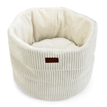 Helle Haustierbett in Cremefarbe mit gerippter Außenseite und weichem Innenraum, mit einem kleinen braunen Lederetikett.