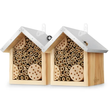 Holz-Bienenhaus mit einem Metalldach, das verschiedene große Löcher für einsame Bienen aufweist, und einer Biene, die auf dem Dach ruht.