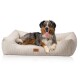 Ein glücklicher Australian Shepherd Hund, der auf einem plüschigen, beigen Hundebett mit strukturiertem Stoff liegt, mit einem kleinen Logo-Tag.