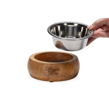Eine Hand hält eine Edelstahlschüssel für Haustiere über einem Holzsockel, auf dem "Designed by Lotte" eingraviert ist.