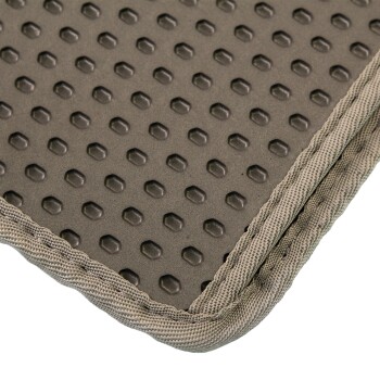 Nahaufnahme einer strukturierten Haustiermatte mit einer gummierten Oberfläche mit kleinen erhöhten sechseckigen Mustern und einem gestickten beigen Rand.