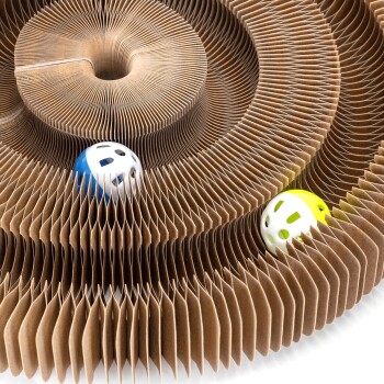 Ein kreisförmiges, geschichtetes Pappspielzeug für Katzen mit zwei kleinen Bällen, einem blauen und einem gelben, die in seinen Rillen liegen.