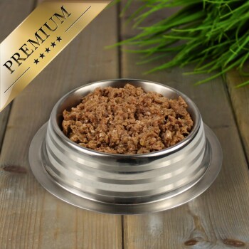 Edelstahlnapf für Haustiere gefüllt mit hochwertigem Nassfutter für Hunde auf einer Holzoberfläche mit grüner Pflanze im Hintergrund.