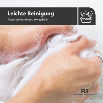 Hände waschen ein weißes Kissen in seifigem Wasser, mit dem Text "Leichte Reinigung - Kissen per Handwäsche waschbar" darüber.