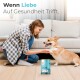Eine Frau in einem karierten Hemd spielt mit einem glücklichen Corgi in einem gemütlichen Wohnzimmer, mit Tierfutter, das mit "Sensitive Lachs + Truthahn" beschriftet ist, in der Nähe.