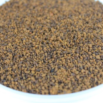 Nahaufnahme von trockenen Haustierfutterkörnern in einer weißen Schüssel, die eine Mischung aus braunen und dunkelbraunen Texturen zeigt.