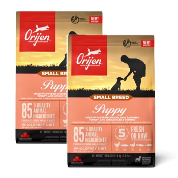 Dwie torby karmy dla szczeniąt Orijen Small Breed z sylwetką osoby i psa o zachodzie słońca, podkreślające "85% jakościowych składników zwierzęcych."
