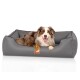 Ein glücklicher Australian Shepherd-Hund, der in einem grauen Haustierbett mit einem Logo-Tag, das "KNUFFELWUFFS" liest, entspannt.