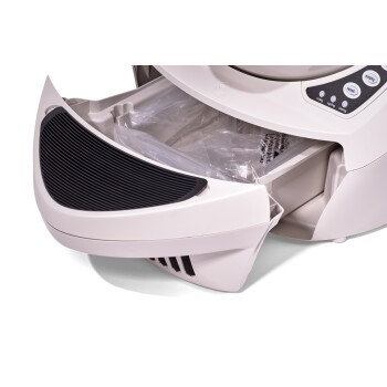 Eine Nahaufnahme eines Haustierfutterspenders mit einem offenen Fach, das eine Plastiktüte im Inneren zeigt, mit Steuerknöpfen an der Seite.